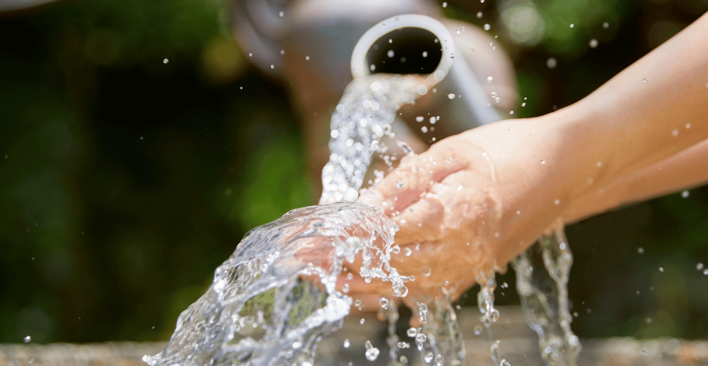 Off-grid water system that is gravity-fed. Man holding his hand under the water stream.