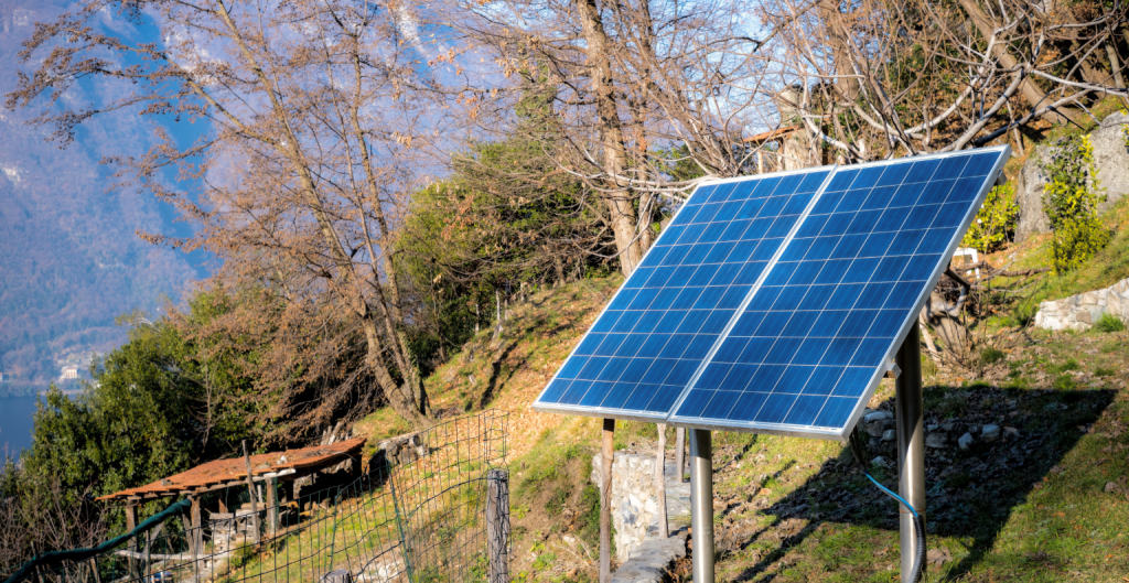Free-standing off-grid solar panel array mounted on a rural hillside property.