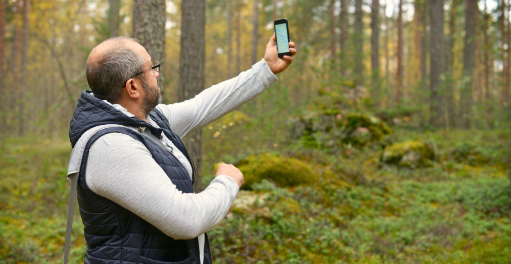 Man holding phone trying to connect to satellite or get signal off grid.