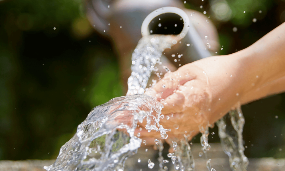 Off-grid water system that is gravity-fed. Man holding his hand under the water stream.