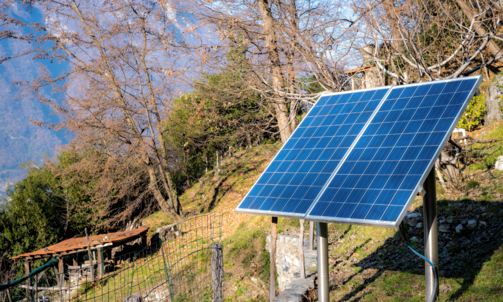 Free-standing off-grid solar panel array mounted on a rural hillside property.