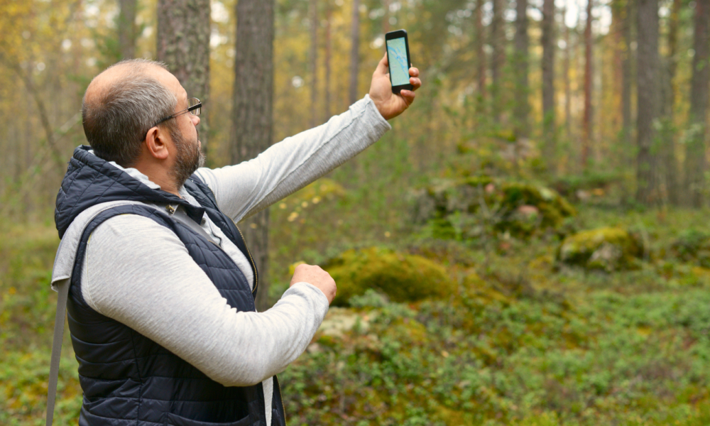 Man holding phone trying to connect to satellite or get signal off grid.