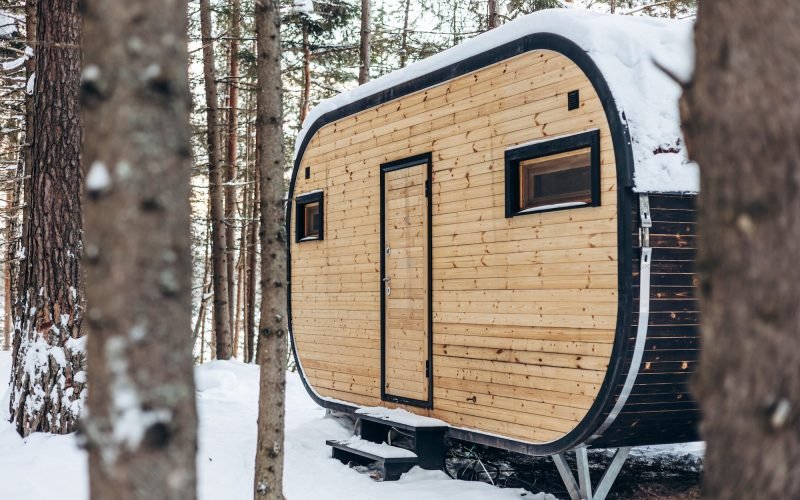 Wooden tiny house snowy winter forest. Glamping
